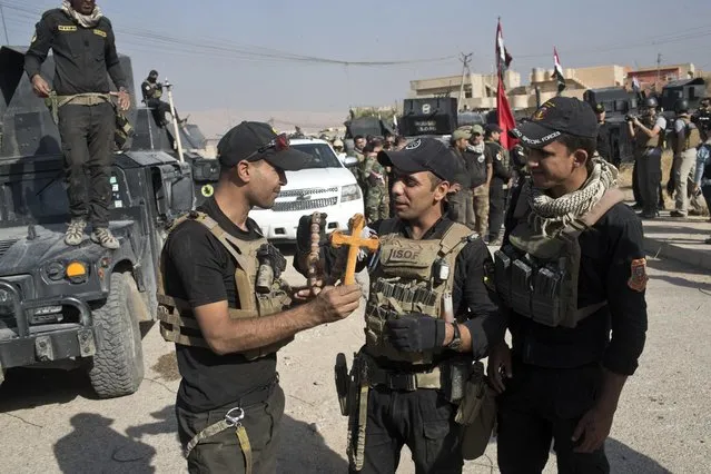Iraqi Special Forces soldiers hold a cross found in the town of Bartella, Iraq, Saturday, October 22, 2016. Iraqi forces retook Bartella, around 15 kilometers east of Mosul, earlier this week, but are still facing pockets of resistance in the area. (Photo by Marko Drobnjakovic/AP Photo)