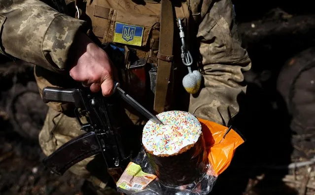 Vasilii (34), service man with Ukraine’s 80th brigade, slices an Easter cake in a forward position during heavy fighting amid Russia’s attack on Ukraine, close to Bakhmut Ukraine on April 16, 2023. (Photo by Kai Pfaffenbach/Reuters)