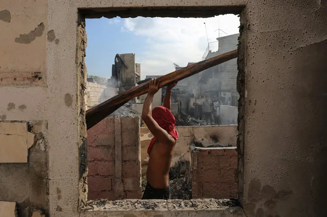 A Filipino carries a metal roof following a fire in Mandaluyong City, east of Manila, Philippines, 26 November 2015. At least 1,000 families were displaced after a fire razed through homes in a residential area in Mandaluyong City, reports said. (Photo by Mark R. Cristino/EPA)