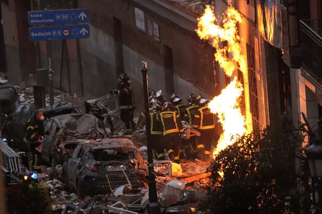 Fire-fighters carry a dead body next to a damaged building at Toledo Street following an explosion in downtown Madrid, Spain, Wednesday, January 20, 2021. A powerful explosion apparently caused by a gas leak has ripped the facade off a residential building in central Madrid. (Photo by Manu Fernandez/AP Photo)