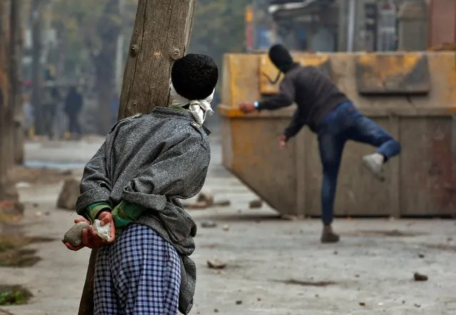 A demonstrator hurls a stone towards the Indian police as another looks on during an anti-India protest in Srinagar, November 4, 2016. (Photo by Danish Ismail/Reuters)