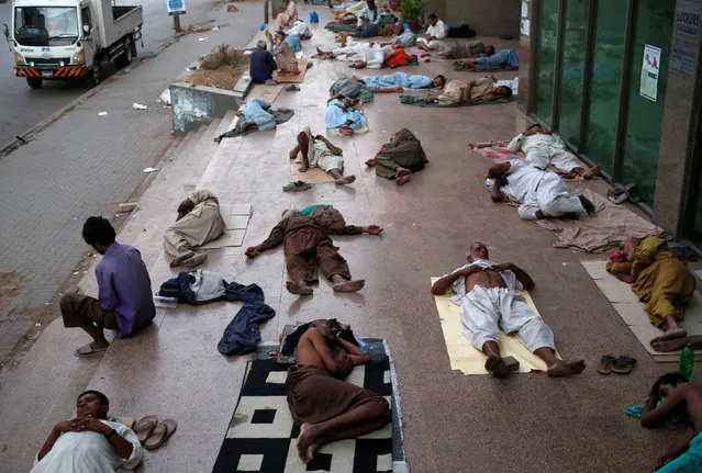Residents sleep on a building pavement, to escape heat and frequent power outage in their residence area Karachi, Pakistan May 22, 2018. (Photo by Akhtar Soomro/Reuters)