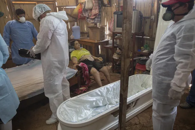 A government team prepares to remove the body of Susana Cifuentes who died in her home from symptoms related to the new coronavirus at the age of 71, in the Shipibo Indigenous community of Pucallpa, in Peru’s Ucayali region, Tuesday, September 1, 2020. While the lucky are cured with ancestral ailments, the less fortunate often die at home. A government team travels from one spartan, thatch-roofed home to the next, removing the dead from their homes where they took their last breaths. (Photo by Rodrigo Abd/AP Photo)
