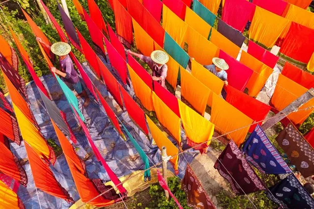 Workers hang hundreds of color-dyed sheets of cloth on a bamboo framework to dry in a dyeing factory in Narayanganj, Bangladesh on May 23, 2023. (Photo by Joy Saha/ZUMA Press Wire/Rex Features/Shutterstock)