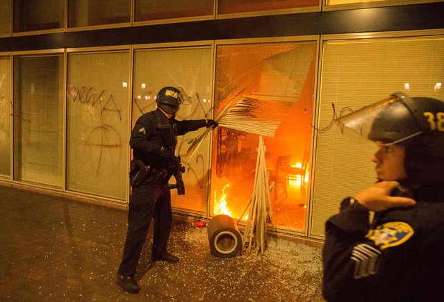 Police investigate a fire lit by protesters during an anti-Trump protest in Oakland, California on November 9, 2016. Thousands of protesters rallied across the United States expressing shock and anger over Donald Trump's election, vowing to oppose divisive views they say helped the Republican billionaire win the presidency. (Photo by Josh Edelson/AFP Photo)