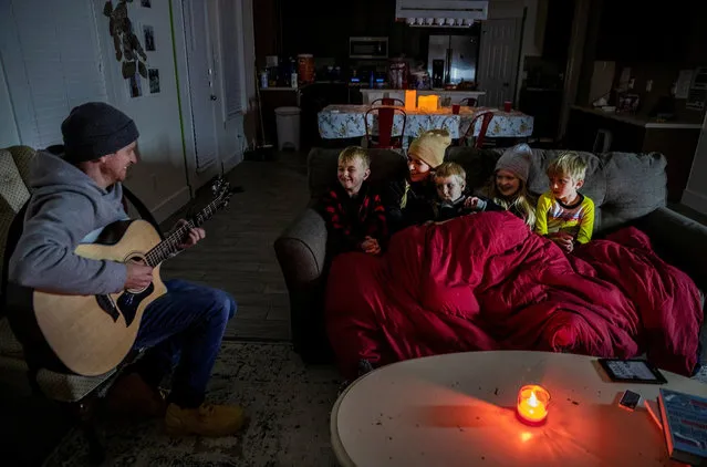 Brett Archibad, whose home was without electric power following winter weather, tries to entertain his family as they try to stay warm in their home the BlackHawk neighborhood in Pflugerville, Texas, U.S. February 16, 2021. (Photo by Ricardo B. Brazziell/American-Statesman/USA Today Network via Reuters)
