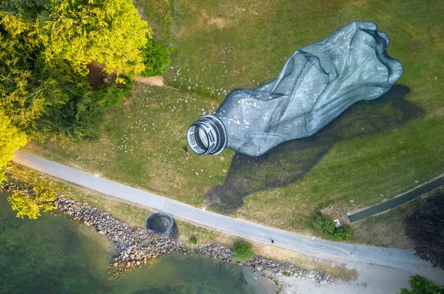 Swiss- French artist SAYPE poses next to his land art painting representing a pet bottle left on the grass as littering in the Parc Bourget in Lausanne, Switzerland on June 16, 2023. (Photo by Denis Balibouse/Reuters)