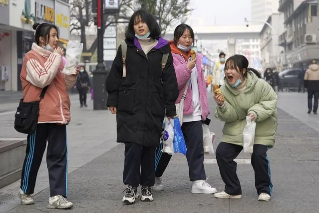 Young girls enjoy a light moment as they visit a popular shopping street in Wuhan in central China's Hubei province on Tuesday, January 26, 2021. (Photo by Ng Han Guan/AP Photo)
