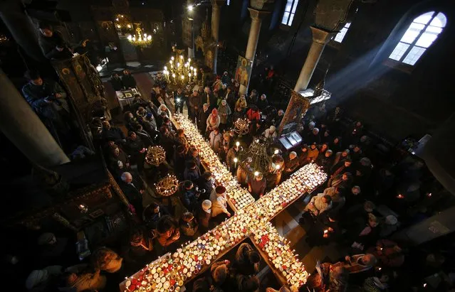 Worshippers gather around candles stuck to jars with honey, during a religious mass in the church of the Presentation of the Blessed Virgin in the city of Blagoevgrad, Bulgaria February 10, 2015. The day of Saint Haralampi, the Orthodox patron saint of beekeepers, is marked on February 10. (Photo by Stoyan Nenov/Reuters)