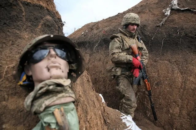 An Ukrainian serviceman walks in a trench by a sort of mannequin as he stands at his post on the frontline with Russia backed separatists near the town of Zolote, in the Lugansk region on April 8, 2021. Ukrainian President Volodymyr Zelensky was travelling to the country's eastern frontline on April 8, 2021, after a surge in clashes with separatist forces and a spike in tensions with Moscow. Fighting between the Ukrainian army and separatists has intensified in recent weeks, raising fears of a major escalation in the long-running conflict over the mainly Russian-speaking Donbas region. (Photo by AFP Photo/Stringer)