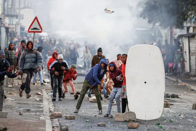 Residents of Masiphumelele throw bottles at police amidst an ongoing strike by taxi operators against traffic authorities in Cape Town, South Africa on August 8, 2023. (Photo by Nic Bothma/Reuters)