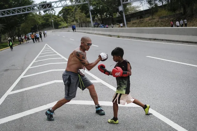 A young boxer trains with his coach on Boyaca Avenue in Caracas, Venezuela, Sunday, April 11, 2021, amid the new coronavirus pandemic. (Photo by Matias Delacroix/AP Photo)