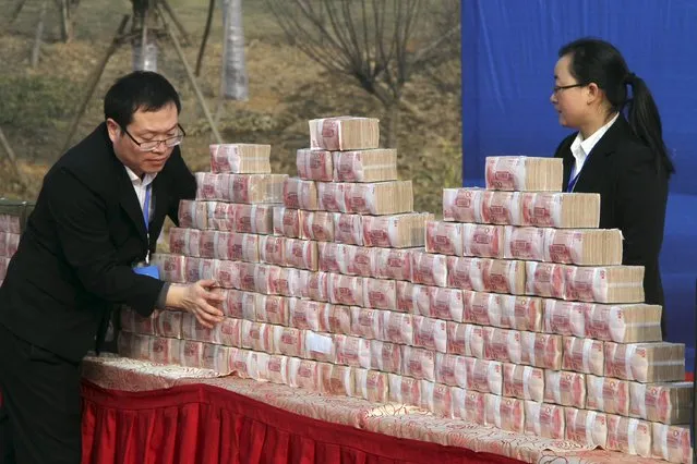 Staff members of a real estate developer pile up bundles of 100 yuan banknotes during a ceremony to give salaries to their construction workers, in Luoyang, Henan province, China, January 9, 2016. The developer gave away 20 million yuan ($3.05 million) in salaries to its workers on Saturday, according to local media. (Photo by Reuters/Stringer)