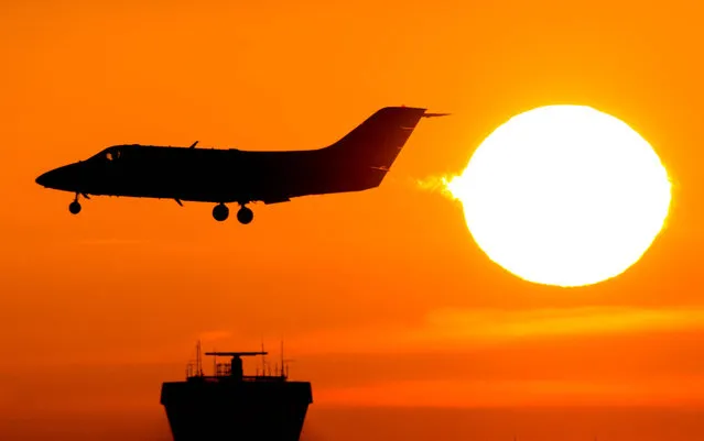 A plane lands in front of the rising sun at the airport in Duesseldorf, Germany, Friday, November 25, 2016. (Photo by Marcel Kusch/DPA via AP Photo)