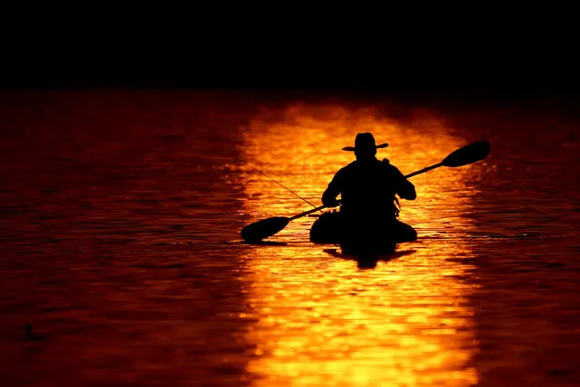 A man kayaks at the end of a warm spring day on Shawnee Mission Lake Saturday, April 3, 2021, in Shawnee, Kan. (Photo by Charlie Riedel/AP Photo)