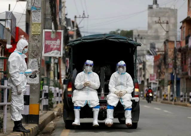 Members of Nepal army personnel wearing personal protective equipment (PPE) rest on a vehicle as they wait to transport a body of a person who died from coronavirus disease (COVID-19) to the crematorium, while Nepal is overwhelmed by a COVID-19 surge as India's outbreak spreads across South Asia, in Kathmandu, Nepal on May 5, 2021. (Photo by Navesh Chitrakar/Reuters)