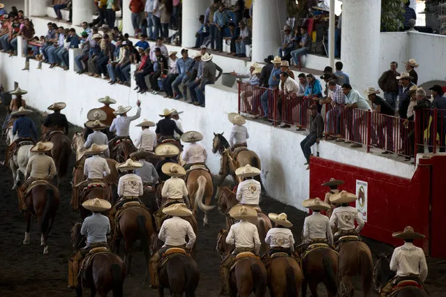 In this February 26, 2015 photo, teams ride in procession out of the ring after the opening of a charreada in Mexico City. “The future of the charreria”, said National Charros Association President Manuel Basurto Rojas, “is to educate the entire population so that everyone knows what our roots are. With horses, the (Spanish) conquest was done, independence was won, the revolution was made. It's part of Mexican identity”. (Photo by Rebecca Blackwell/AP Photo)