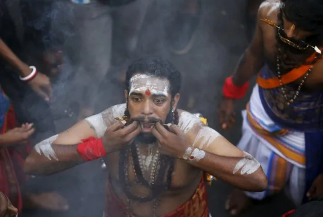 A Hindu devotee reacts after his cheeks are pierced during Thaipusam at Batu Caves in Kuala Lumpur, Malaysia, January 23, 2016. (Photo by Olivia Harris/Reuters)