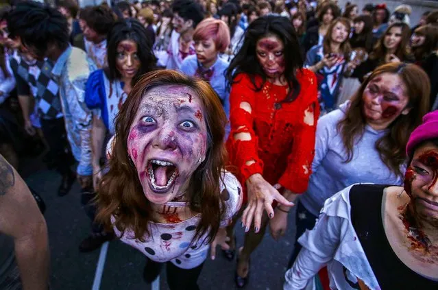 Participants wearing costumes and make-up as zombies march during a Halloween event to promote the U.S. TV series “The Walking Dead” at Tokyo Tower, on Oktober 31, 2013. More than a thousand people dressed as zombies participated in the event to simulate taking over the tower. (Photo by Issei Kato/Reuters)