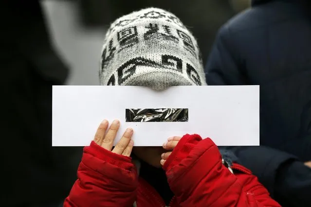 A boy holds home-made protective glasses outside The Royal Observatory during a partial solar eclipse in Greenwich, south east London March 20, 2015. (Photo by Stefan Wermuth/Reuters)