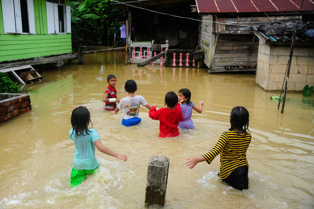Children play near houses inundated by floodwaters after heavy rains in the Rangae district of the southern province of Narathiwat, Thailand on December 21, 2016. (Photo by Madaree Tohlala/AFP Photo)