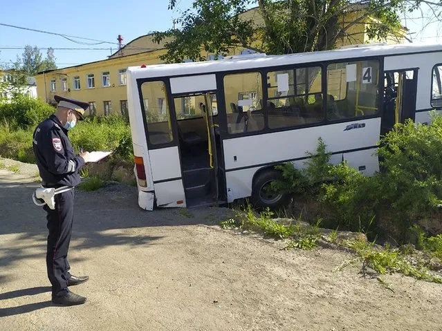 In this photo provided by Russian Interior Ministry, a Russian police officer stands near the bus which crashed into a bus stop in the town of Lesnoy about 1,350 kilometers (840 miles) east of Moscow, Russia, Thursday, June 10, 2021. A bus crashed into a bus stop in Russia's Sverdlovsk region on Thursday morning, killing six people and injuring 15 others, local officials said. The bus was carrying workers to a plant in the town of Lesnoy about 1,350 kilometers (840 miles) east of Moscow. (Photo by Russian Interior Ministry via AP Photo)