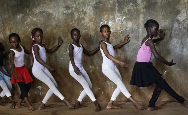 In this photo taken Friday, December 9, 2016, young ballerinas practice under the instruction of Kenyan ballet dancer Joel Kioko, 16, in a room at a school in the Kibera slum of Nairobi, Kenya. (Photo by Ben Curtis/AP Photo)