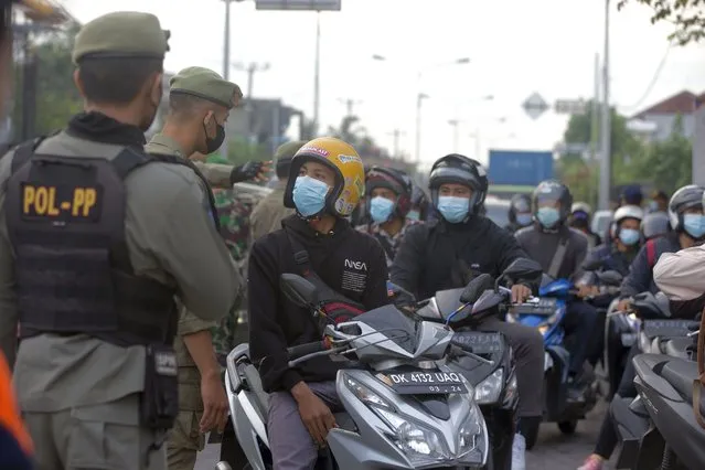 Security officers check motorcyclists at a check point during the imposition of an emergency restriction to curb the spread of coronavirus outbreak in Denpasar, Bali, Indonesia on Thursday, July 8, 2021. Indonesia is facing a coronavirus surge as hospitals grapple with soaring cases amid widespread shortages of oxygen. (Photo by Firdia Lisnawati/AP Photo)