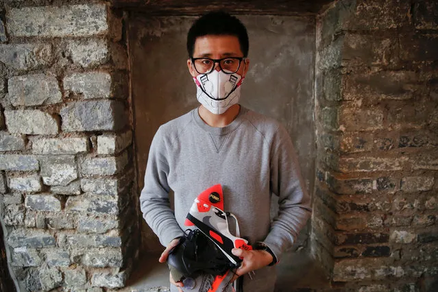 Designer Wang Zhijun poses for pictures, wearing one of the face masks and holding others he made using sneakers, in Beijing, China December 21, 2016. (Photo by Damir Sagolj/Reuters)