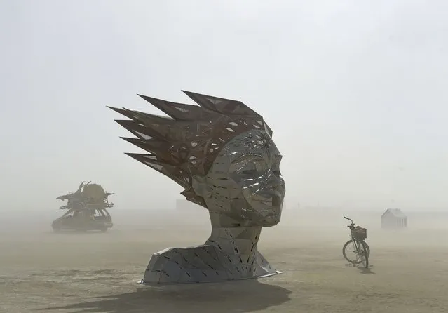 An art car rides past an art piece at Burning Man near Gerlach, Nev. on Friday, August 26, 2022. Burning Man returns after a two-year pandemic shutdown. (Photo by Andy Barron/The Reno Gazette-Journal via AP Photo)