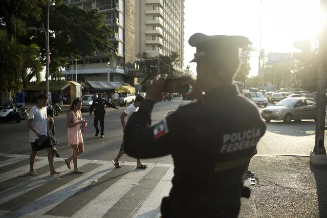 A federal police officer takes a photo of his colleague directing traffic on April 1, 2015 in Acapulco, Mexico. (Photo by Jonathan Levinson/The Washington Post)