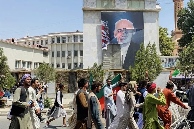 Afghans pass by the poster of Afghan President Ashraf Ghani who fled the country after Taliban took over, as they celebrate the Independence Day in Kabul, Afghanistan, 19 August 2021. Afghanistan's celebrates the 102nd anniversary of its independence from British rule on 18 August. (Photo by EPA/EFE/Stringer)