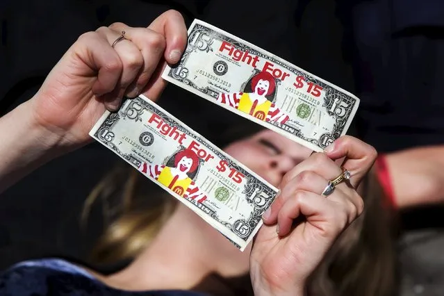 A protester holds mock $15 bills as she participates in a “die in” demonstration for higher wages in the Manhattan borough of New York City April 15, 2015. Fast-food workers rallied on Wednesday for higher pay, using the April 15 tax deadline to publicize their claims that they cannot survive on the hourly wages paid by many U.S. corporations. (Photo by Lucas Jackson/Reuters)