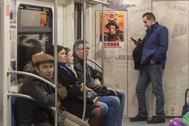 Passengers take a subway train decorated with World War II era posters during its first trip in Moscow, Russia, Wednesday, April 22, 2015. Russia will celebrate the 70th anniversary of the Victory in WWII on May 9, 2015. The poster reads, “Glory to soldier the conqueror!”. (Photo by Denis Tyrin/AP Photo)