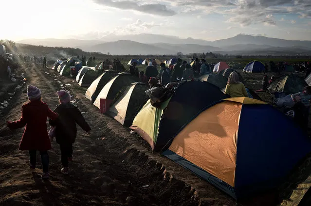 Children walk in the makeshift migrant camp at the Greek-Macedonian border, near the Greek village of Idomeni, on March 2, 2016, where thousands of people are stranded. The EU on March 2 proposed 700 million euros in emergency aid for Greece and other states as it began to tackle the migrant crisis within its borders like humanitarian disasters in developing countries. The United Nations has warned of a looming humanitarian crisis as thousands of people remained stuck in miserable winter conditions on the Greece-Macedonia border after Balkans states and Austria capped the numbers arriving. (Photo by Louisa Gouliamaki/AFP Photo)
