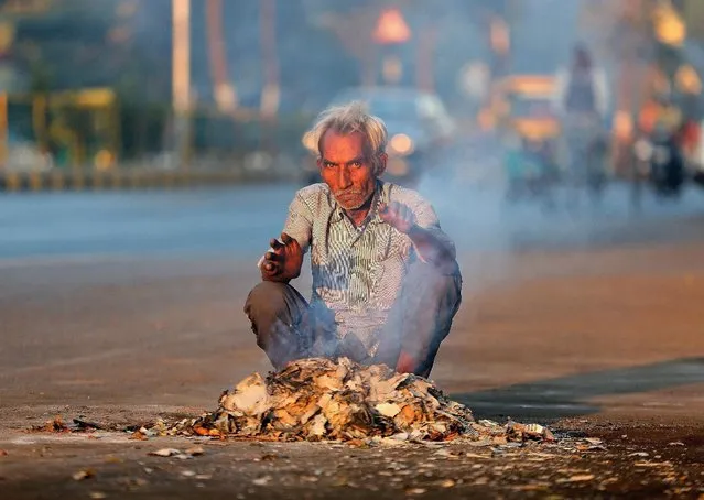 A man looks on as he lights fire to warm himself up alongside a road in Ahmedabad, India January 30, 2017. (Photo by Amit Dave/Reuters)