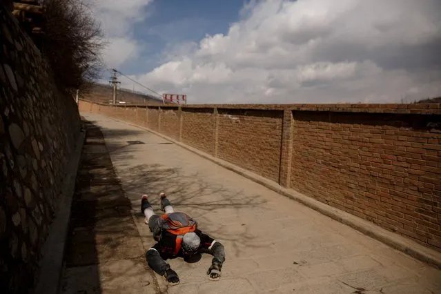 A Tibetan man prostrates himself in prayer as he circles the Tibetan Buddhist Kumbum Monastery outside Xining, Qinghai province, China on March 10, 2019. (Photo by Thomas Peter/Reuters)