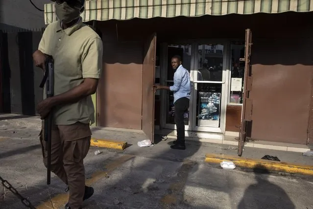 A private security guard stands watch as an employee opens up shop in the Petion-Ville neighborhood of Port-au-Prince, Haiti, early Monday morning, September 27, 2021. For decades, the country was ruled by political strongmen supported by armed gangs; since the assassination of President Jovenel Moise, the state collapsed.. (Photo by Rodrigo Abd/AP Photo)