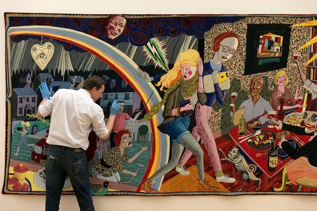 Grayson Perry’s giant tapestry, Expulsion from Number 8 Eden Close, is prepared for an exhibition at the Lightbox Gallery in Woking in the last decade of January 2024. The artwork was inspired by William Hogarth’s A Rake’s Progress. The figure watching the scene from the sky is Jamie Oliver, said to be the god of social mobility. (Photo by Richard Pohle/The Times)