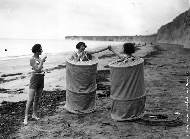 Two women changing discreetly on a beach in Skreenette bathing tents, 1929