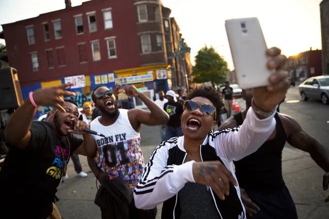 Local rappers from right, Kova, Bilal and Spence sing on a street corner near the scene of some of Monday's rioting following Freddie Gray's funeral, Sunday, May 3, 2015, in Baltimore. (Photo by David Goldman/AP Photo)