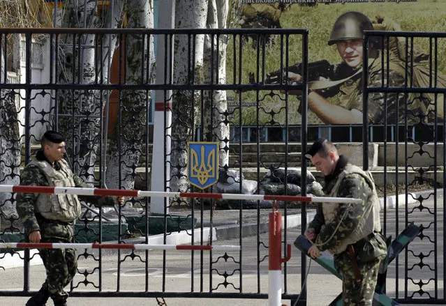 Ukrainian soldiers stand guard at the gate of a military base in the port of Kerch, Ukraine, Monday, March 3, 2014. Pro-Russian troops controlled a ferry terminal on the easternmost tip of Ukraine's Crimea region close to Russia on Monday, intensifying fears that Moscow will send even more troops into the strategic Black Sea region in its tense dispute with its Slavic neighbor. (Photo by Darko Vojinovic/AP Photo)