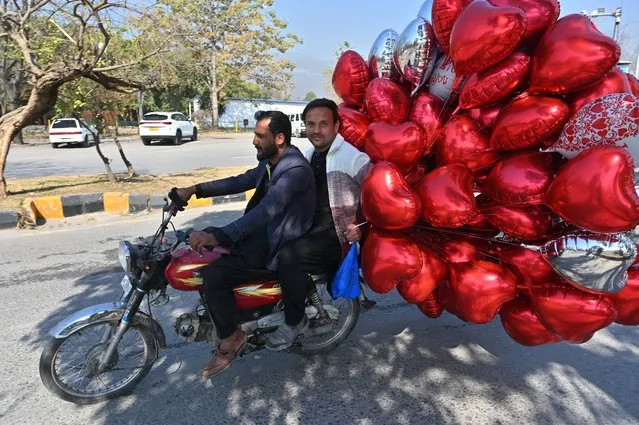 Men ride a bike after buying heart-shaped balloons at a flower market on Valentine's Day in Islamabad on February 14, 2024. (Photo by Farooq Naeem/AFP Photo)