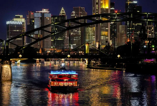 An illuminated party boat cruises over the river Main with the European Central Bank at right in Frankfurt, Germany, Saturday, October 2, 2021. (Photo by Michael Probst/AP Photo)