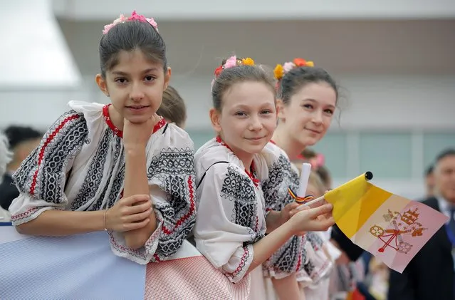 Young girls wearing traditional Romanian clothes and holding a Vatican flag waits for the arrival of Pope Francis from Rome, at Henri Coanda International Airport in Otopeni, near Bucharest, Romania, Friday, May 31, 2019. Pope Francis is heading to Romania for a three-day, cross-country pilgrimage that in many ways is completing the 1999 trip by St. John Paul II that marked the first-ever papal visit to a majority Orthodox country. (Photo by Vadim Ghirda/AP Photo)