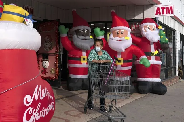 A shopper wearing a face mask pushes an empty cart past inflatable Santa Clauses as she leaves a discount store in Inglewood, Calif., Monday, December 20, 2021. Omicron has raced ahead of other variants and is now the dominant version of the coronavirus in the U.S., accounting for 73% of new infections last week, federal health officials said Monday. (Photo by Jae C. Hong/AP Photo)