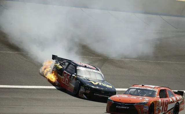 Flames shoot from Jamie Dick's car after he hit the wall during the NASCAR Xfinity series auto race at Charlotte Motor Speedway in Concord, N.C., on Saturday, May 23, 2015. (Photo by Chris Keane/AP Photo)