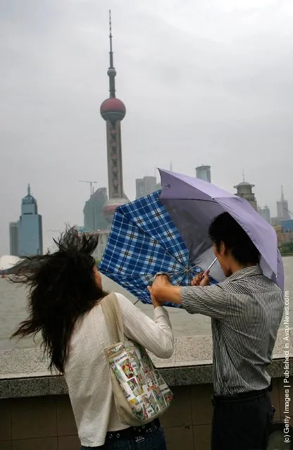 A woman tries to hold her umbrella in big wind triggered by typhoon Wipha at the Bund