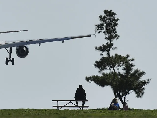 People enjoy the nice weather at Gravelly Point as planes fly above on March 9, 2016 in Arlington, Va. (Photo by Ricky Carioti/The Washington Post)