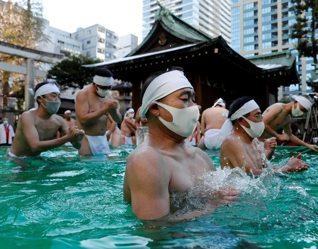 Participants wearing protective face masks amid the coronavirus disease (COVID-19) outbreak, pray as they take an ice-cold bath during a ceremony to purify their souls and to wish for overcoming the pandemic at the Teppozu Inari shrine in Tokyo, Japan on January 9, 2022. (Photo by Kim Kyung-Hoon/Reuters)
